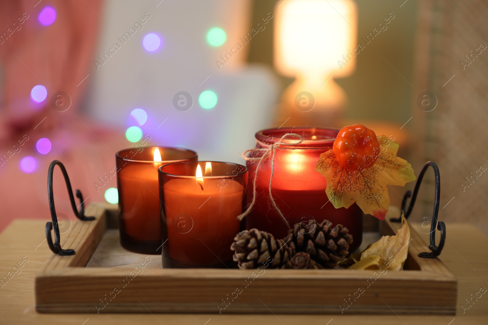 Photo of Burning candles and autumn decor on wooden table indoors