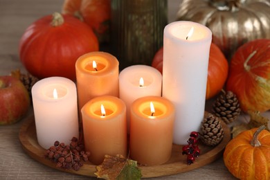 Photo of Tray with many burning candles and autumn decor on wooden table, closeup