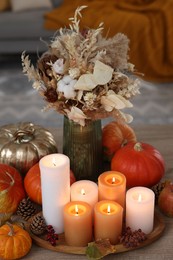 Photo of Tray with many burning candles and autumn decor on wooden table indoors