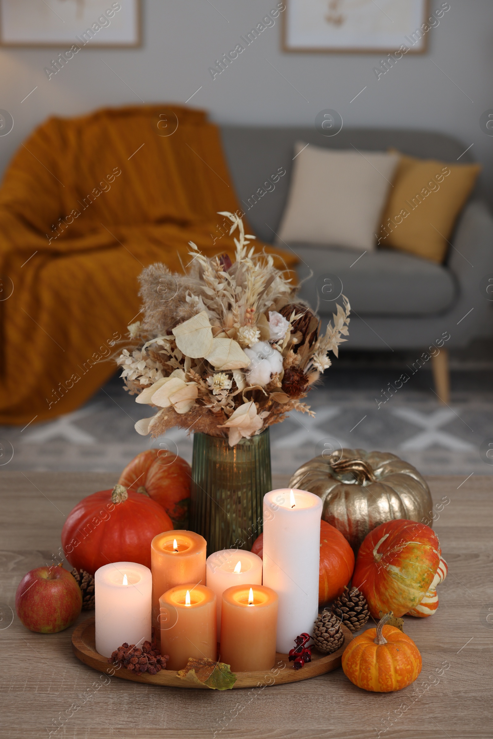 Photo of Tray with many burning candles and autumn decor on wooden table indoors