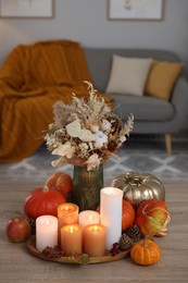 Photo of Tray with many burning candles and autumn decor on wooden table indoors