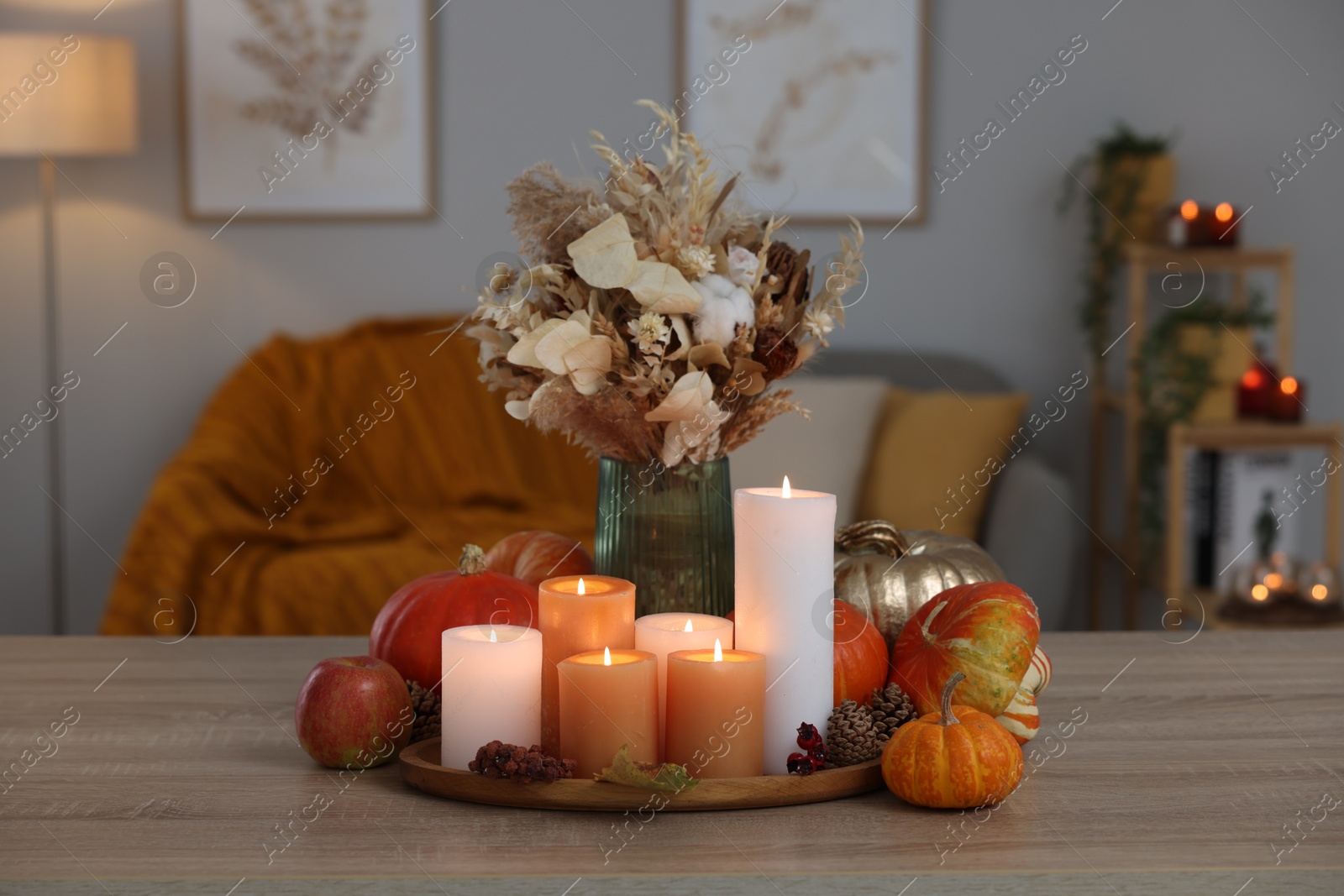 Photo of Tray with many burning candles and autumn decor on wooden table indoors