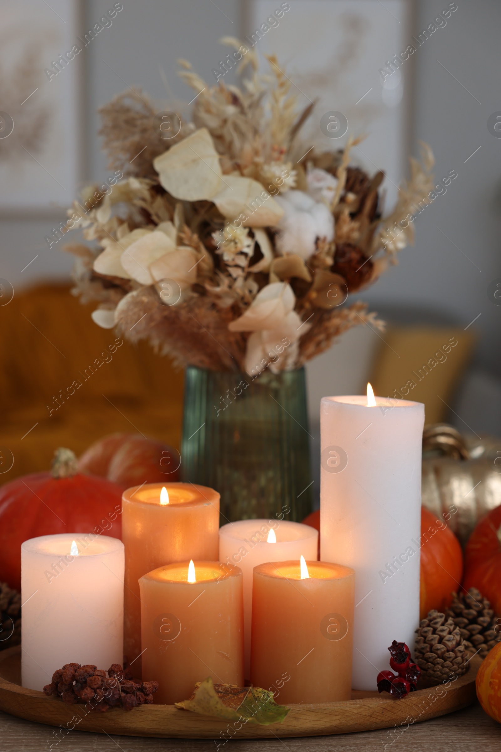 Photo of Tray with many burning candles and autumn decor on wooden table indoors, closeup