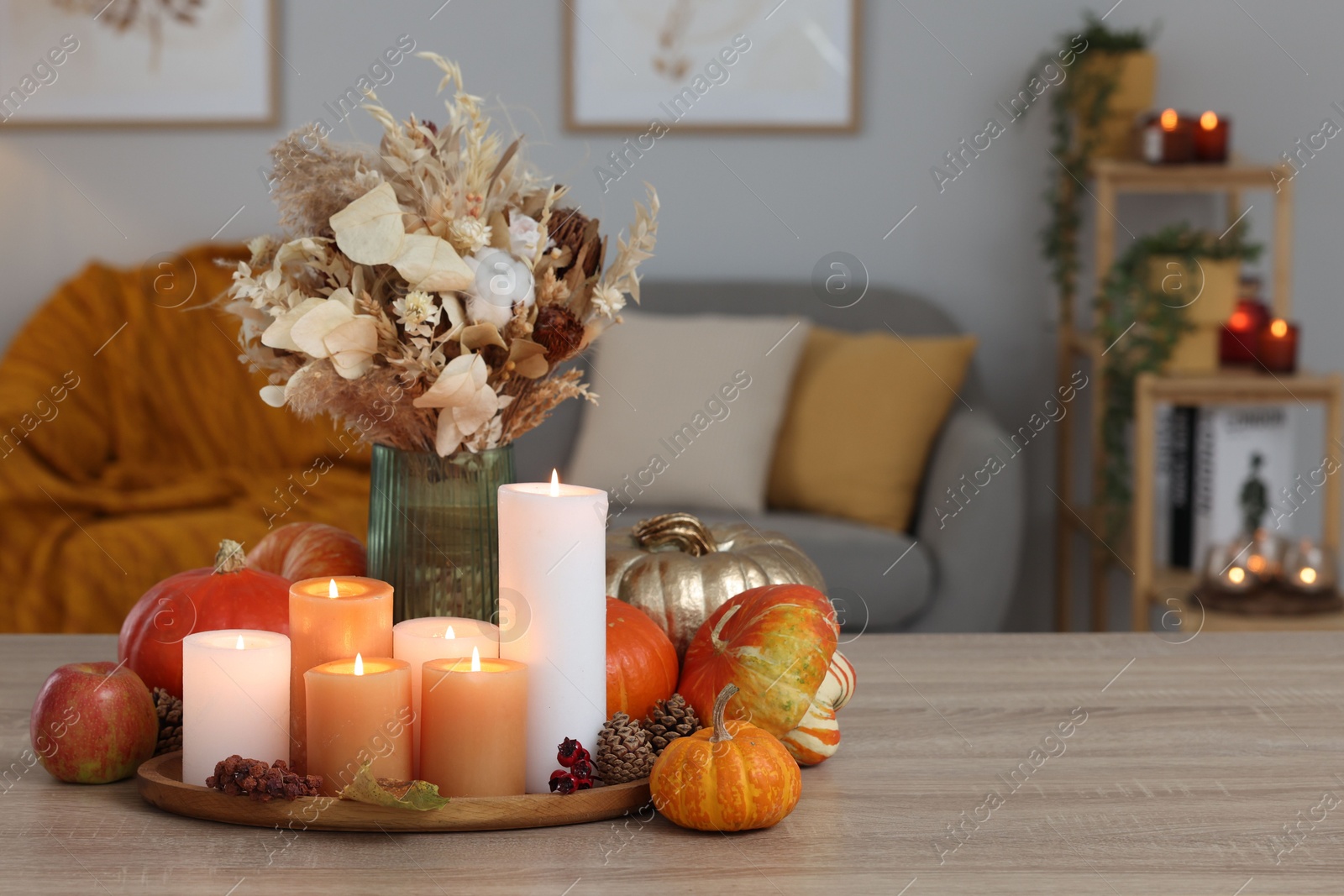 Photo of Tray with many burning candles and autumn decor on wooden table indoors. Space for text