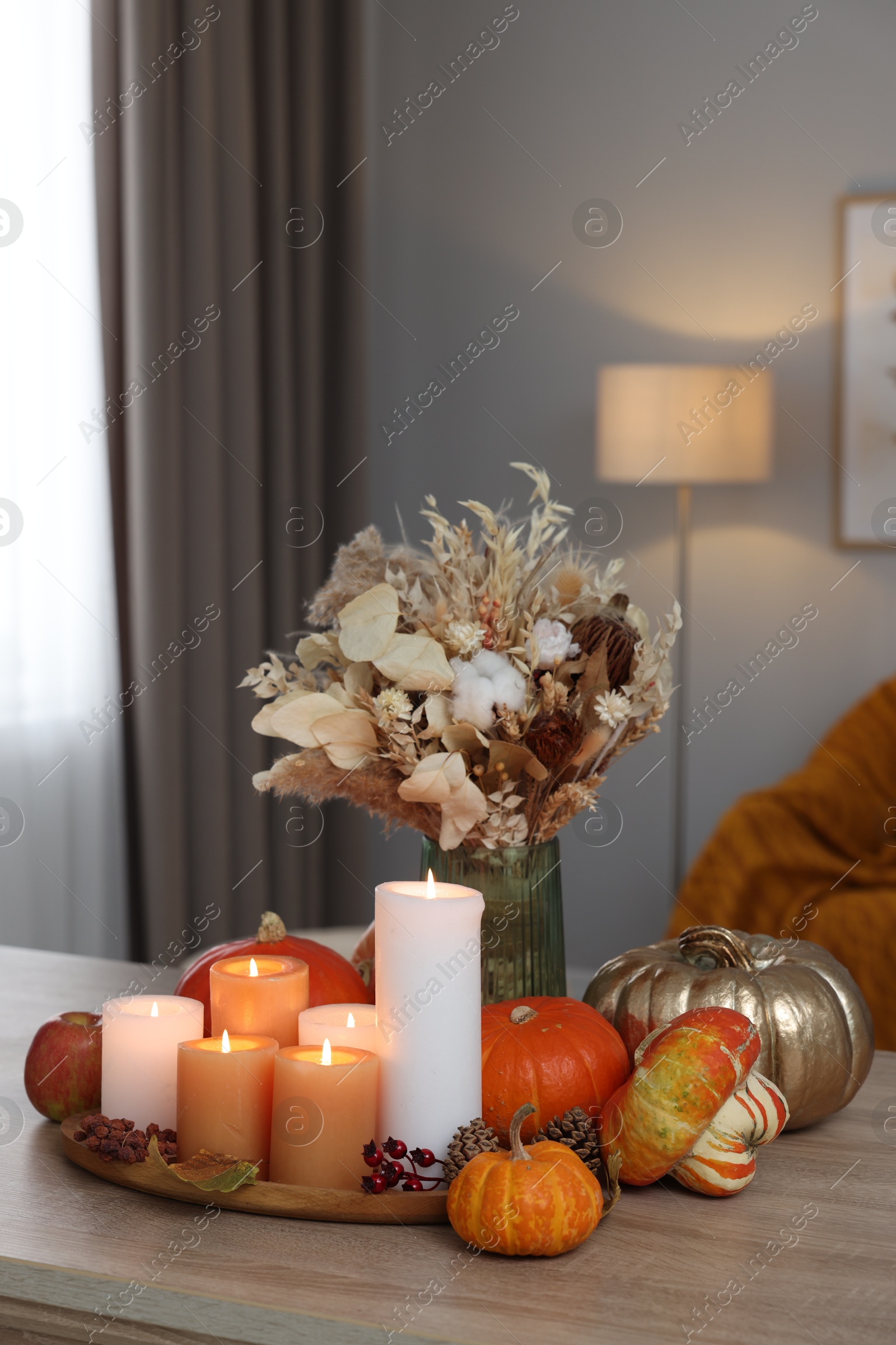 Photo of Tray with many burning candles and autumn decor on wooden table indoors