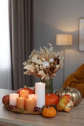 Photo of Tray with many burning candles and autumn decor on wooden table indoors