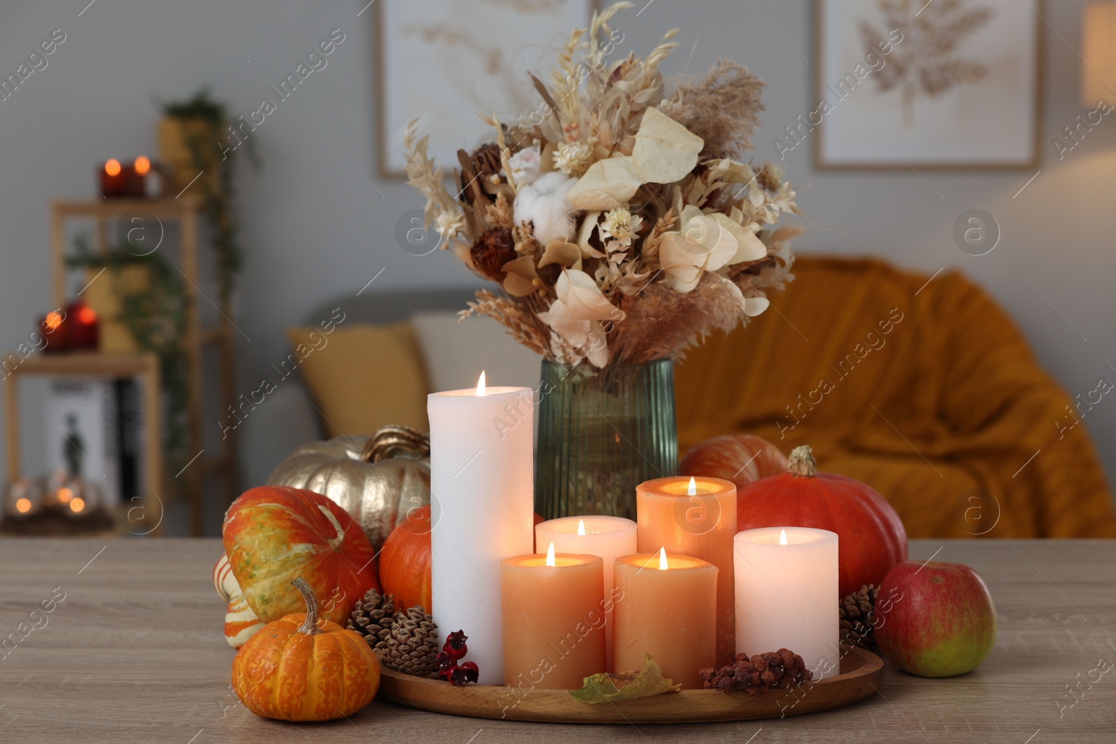 Photo of Tray with many burning candles and autumn decor on wooden table indoors