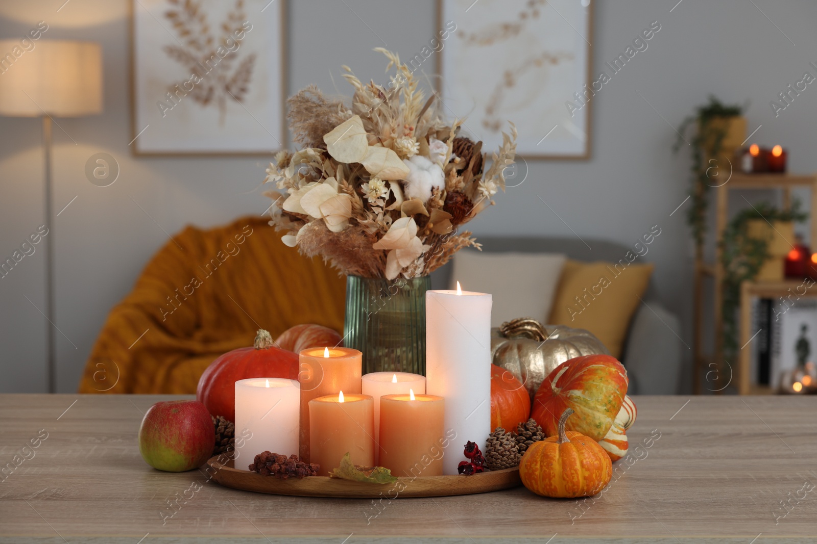 Photo of Tray with many burning candles and autumn decor on wooden table indoors