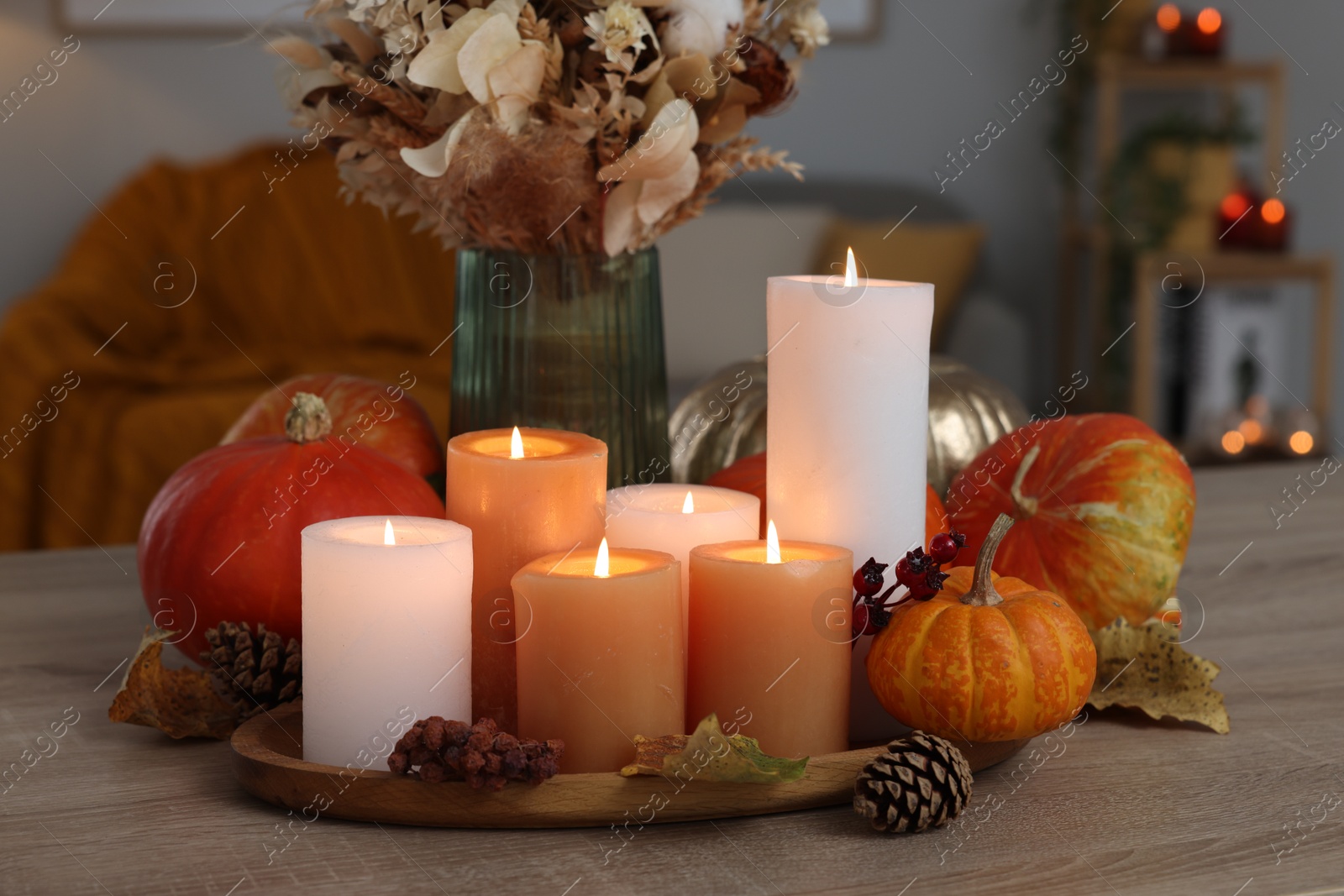 Photo of Tray with many burning candles and autumn decor on wooden table indoors