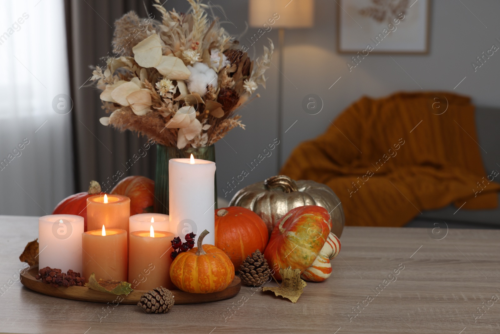 Photo of Tray with many burning candles and autumn decor on wooden table indoors. Space for text