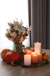 Photo of Tray with many burning candles and autumn decor on wooden table indoors