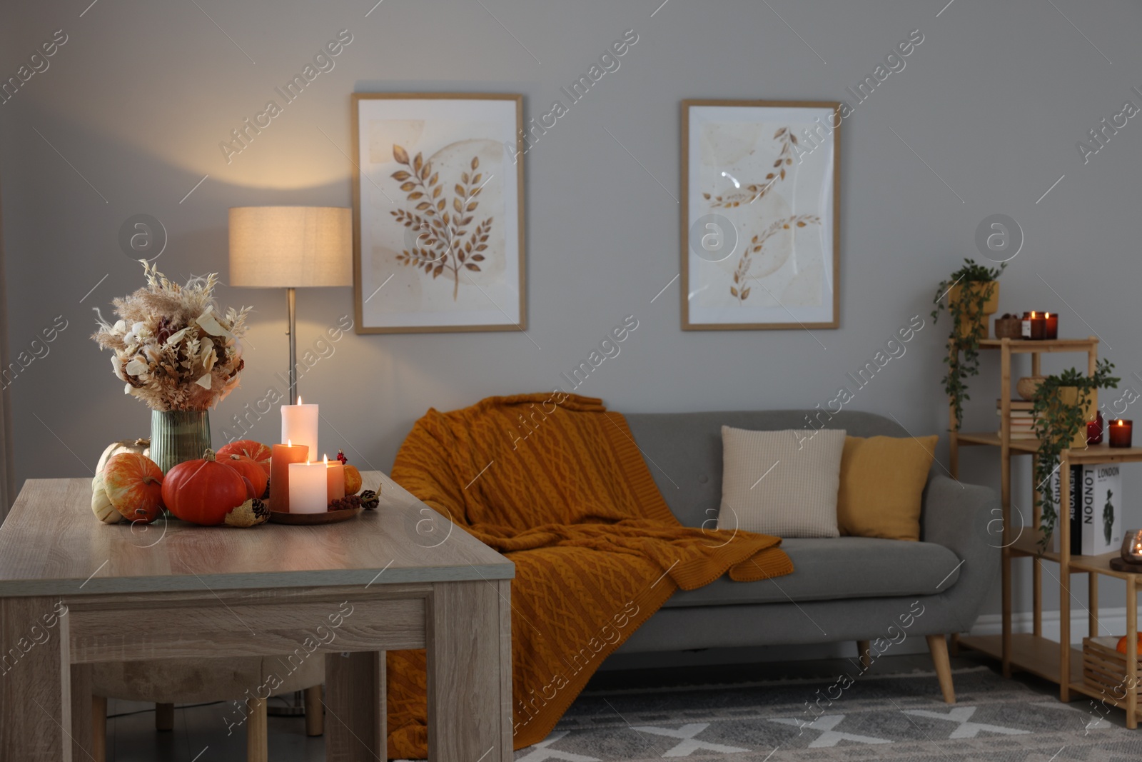 Photo of Burning candles and stylish furniture in cozy room. Autumn atmosphere