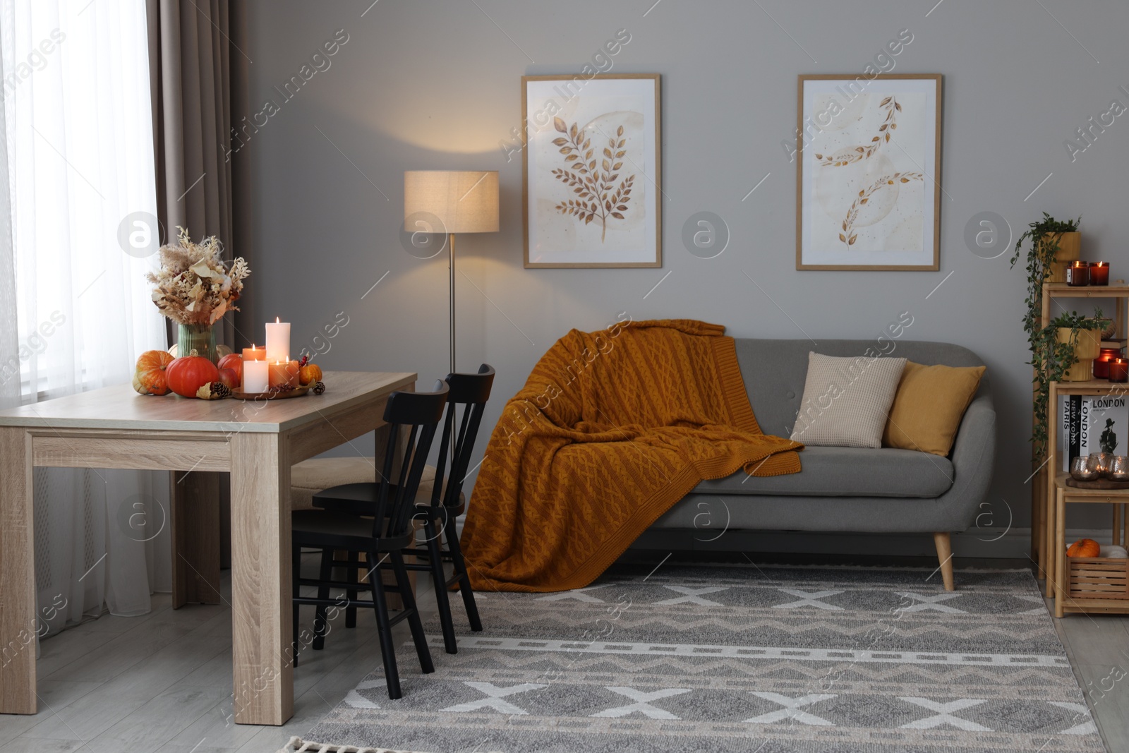 Photo of Burning candles and stylish furniture in cozy room. Autumn atmosphere