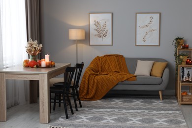 Photo of Burning candles and stylish furniture in cozy room. Autumn atmosphere