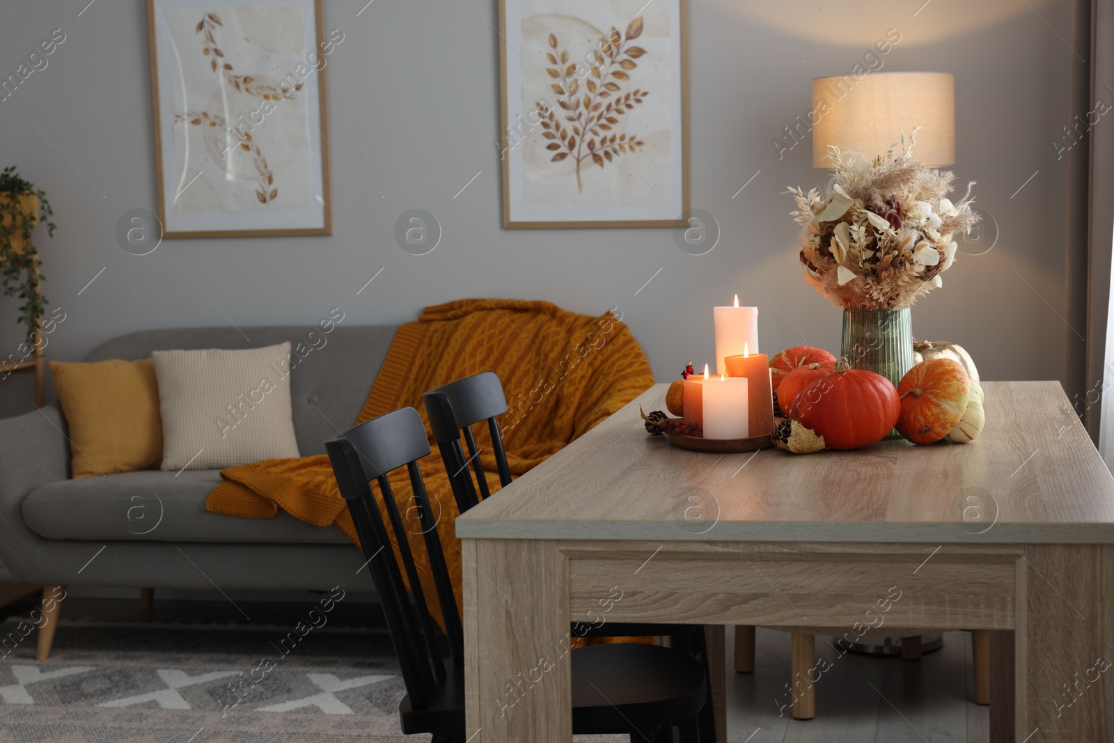 Photo of Burning candles and stylish furniture in cozy room. Autumn atmosphere