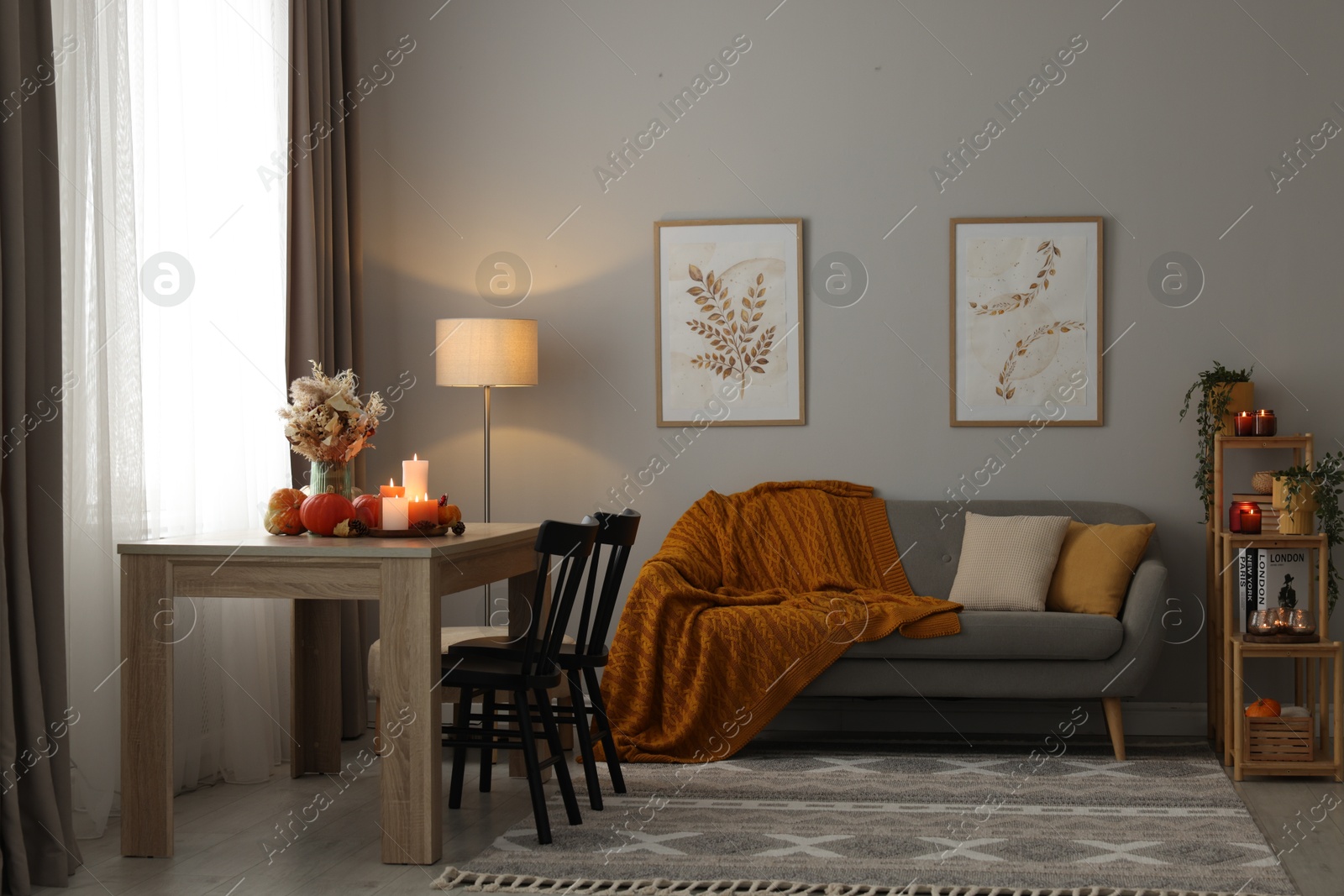 Photo of Burning candles and stylish furniture in cozy room. Autumn atmosphere