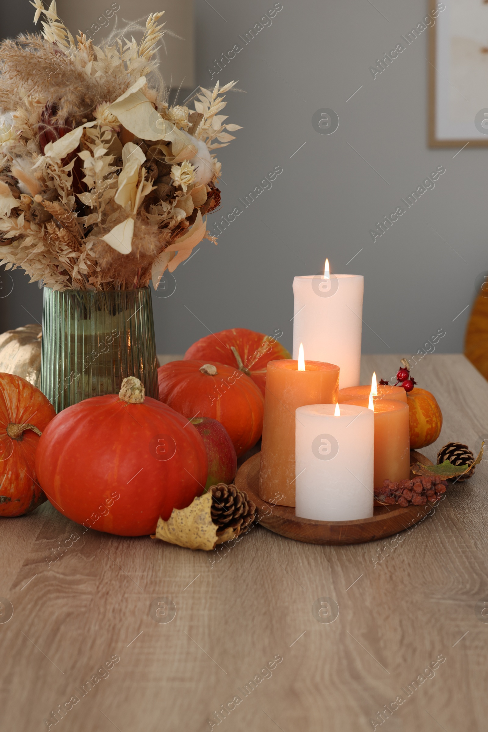 Photo of Tray with many burning candles and autumn decor on wooden table indoors