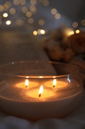 Photo of Burning candle on white cloth, closeup. Cozy atmosphere