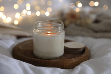 Photo of Burning candle on white cloth, closeup. Cozy atmosphere