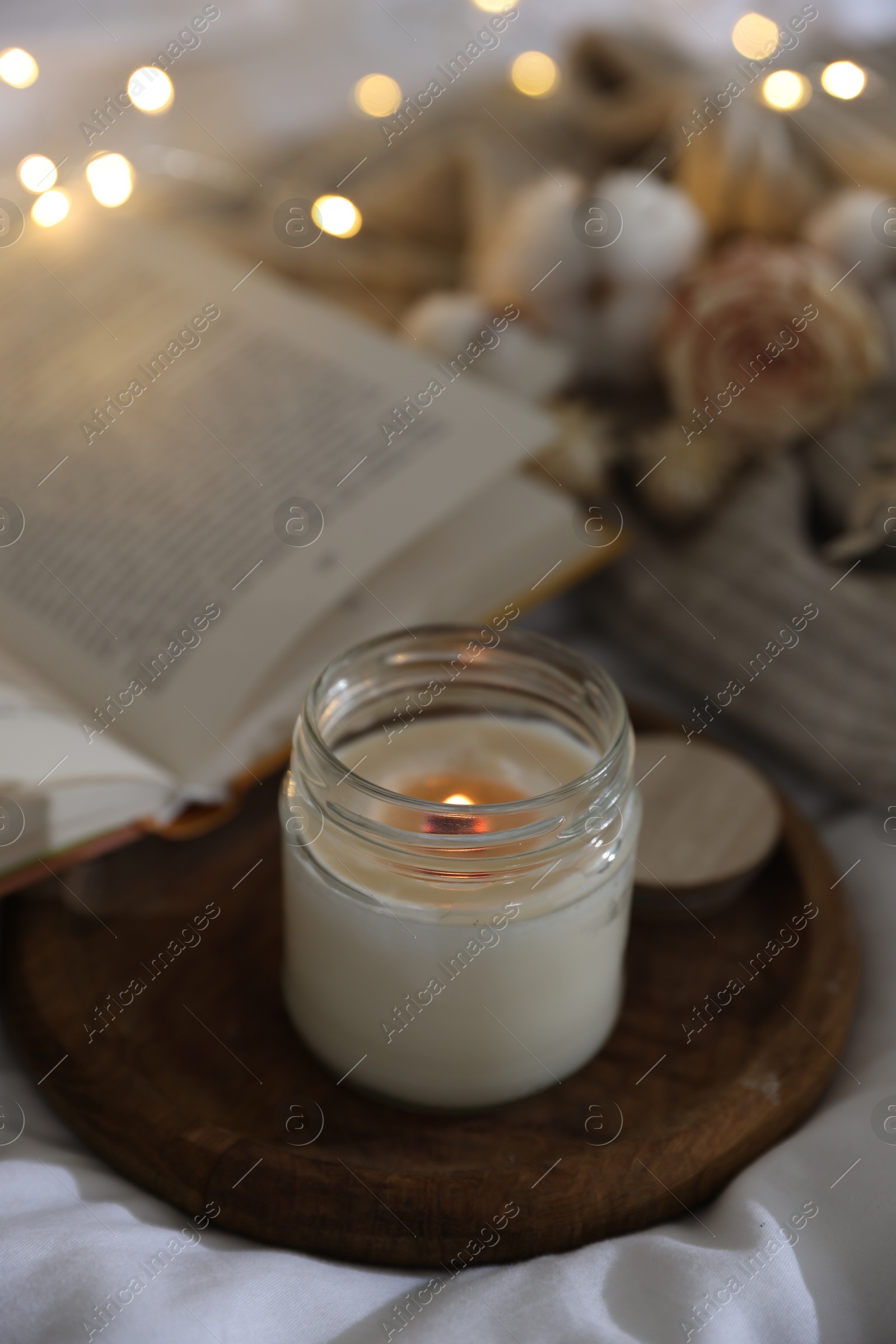 Photo of Burning candle on white cloth. Cozy atmosphere