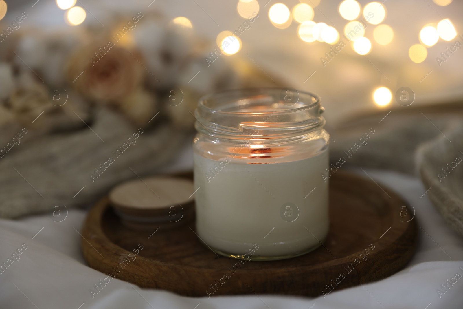 Photo of Burning candle on white cloth, closeup. Cozy atmosphere