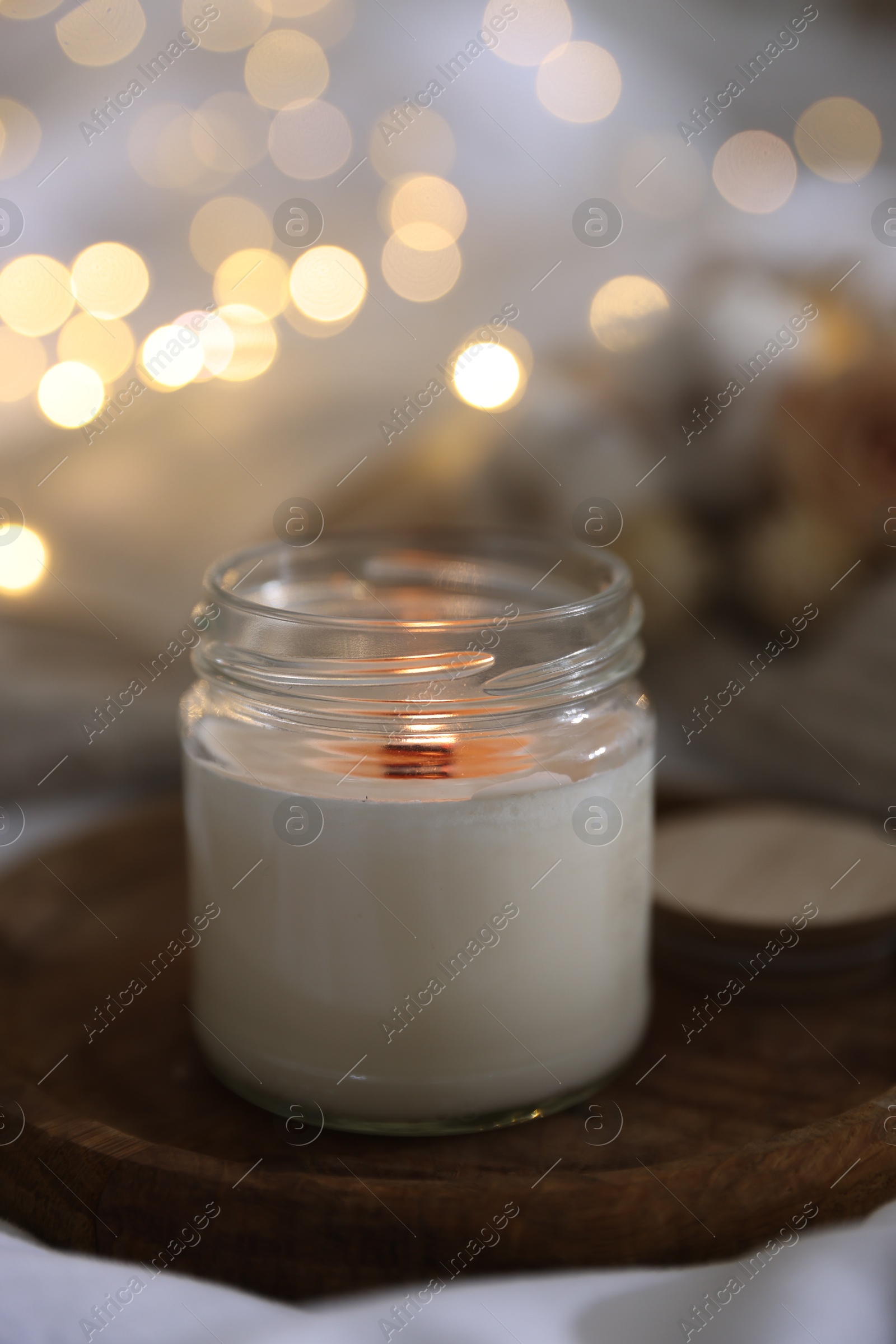 Photo of Burning candle on white cloth, closeup. Cozy atmosphere