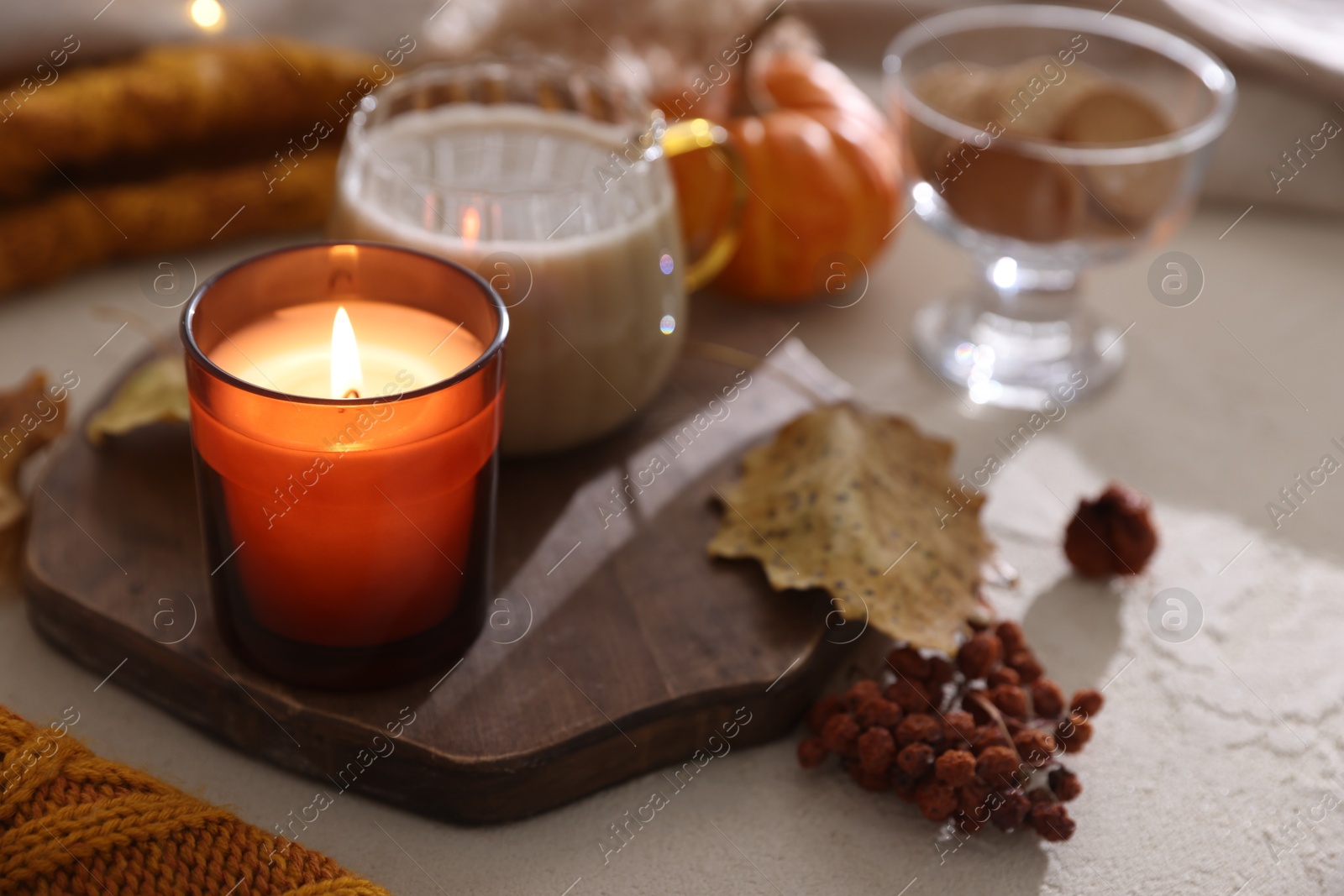 Photo of Burning candle on light textured table, closeup. Autumn atmosphere