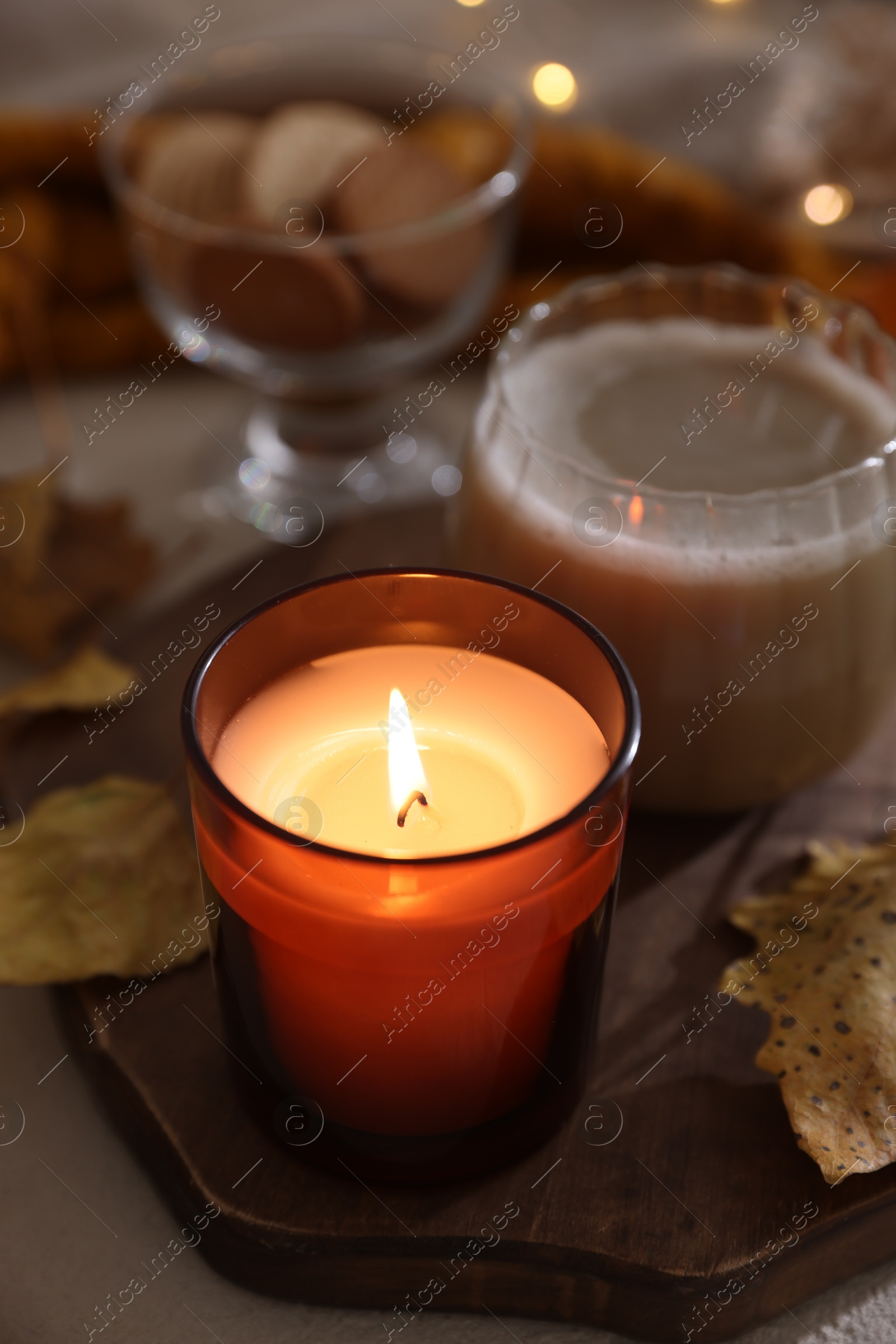 Photo of Burning candle on textured table, closeup. Autumn atmosphere