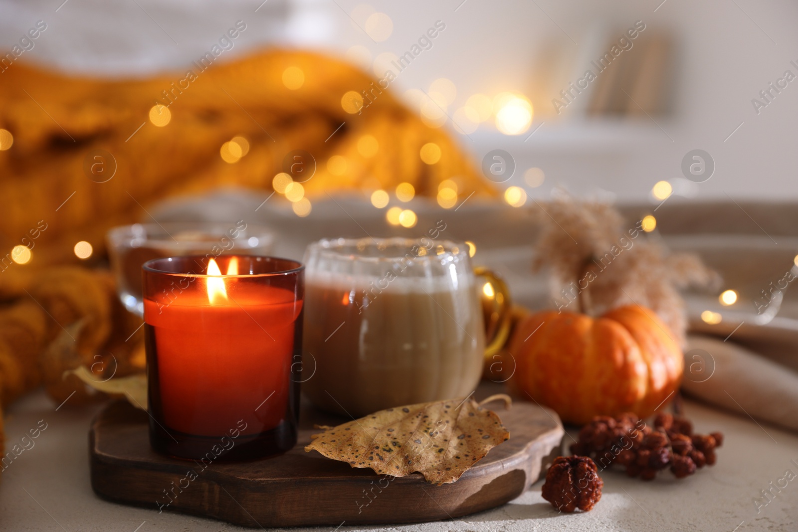 Photo of Burning candle and autumn decor on light table, closeup. Cozy atmosphere