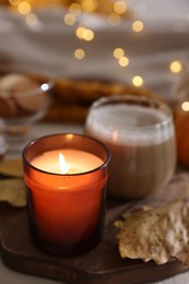 Photo of Burning candle and dry leaf on light table, closeup. Autumn atmosphere