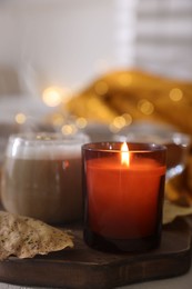 Photo of Burning candle and dry leaf on light table, closeup. Autumn atmosphere