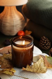 Photo of Burning candle and dry leaves on open book. Autumn atmosphere