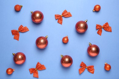 Photo of Christmas balls and bows on blue background, flat lay