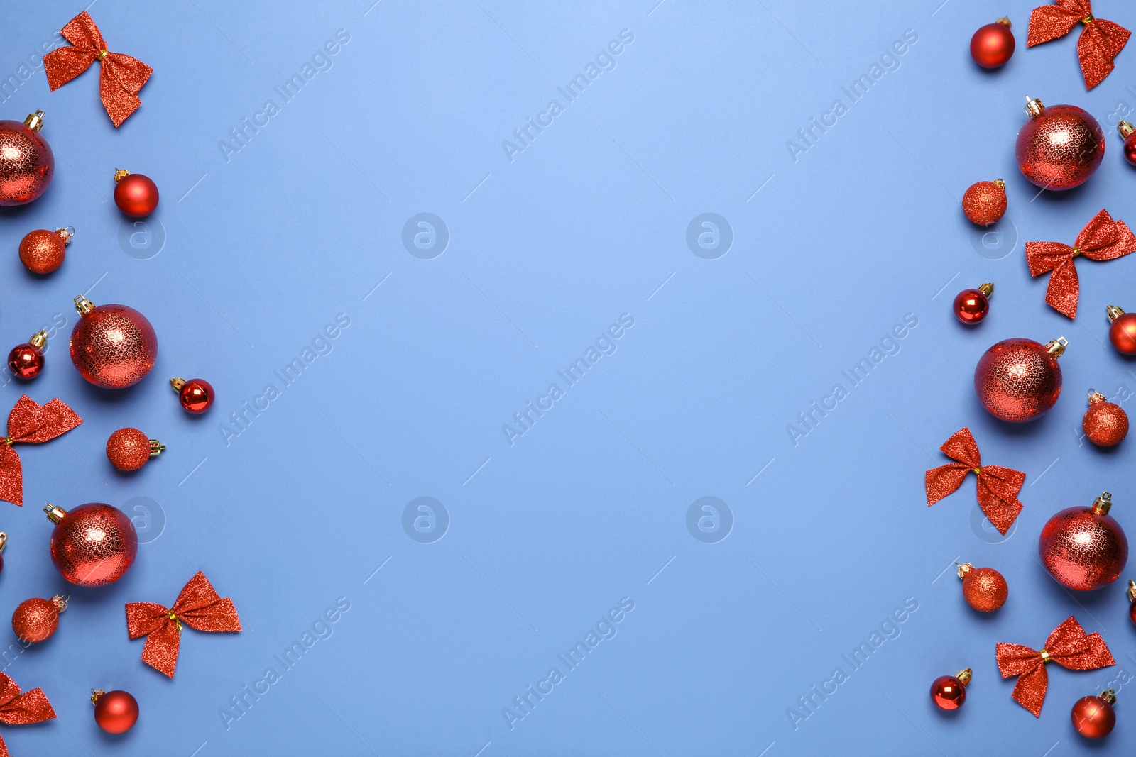 Photo of Christmas balls and bows on blue background, flat lay. Space for text