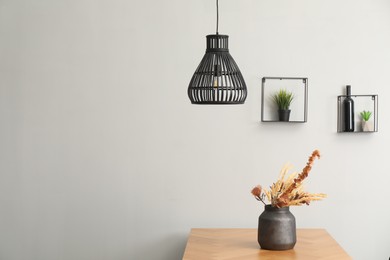 Photo of Vase with bouquet of dried flowers on wooden table indoors. Space for text