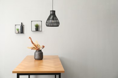 Photo of Vase with bouquet of dried flowers on wooden table indoors. Space for text