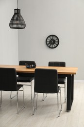 Photo of Wooden table with black chairs in stylish dining room