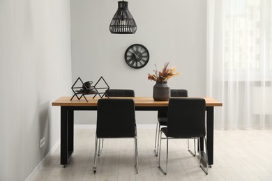 Photo of Wooden table with black chairs in stylish dining room