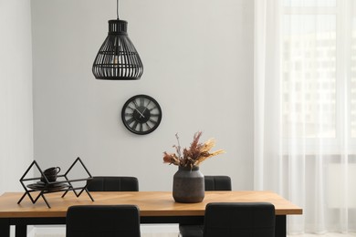 Photo of Wooden table with black chairs in stylish dining room