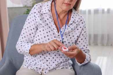 Photo of Senior woman pressing emergency call button at home, closeup