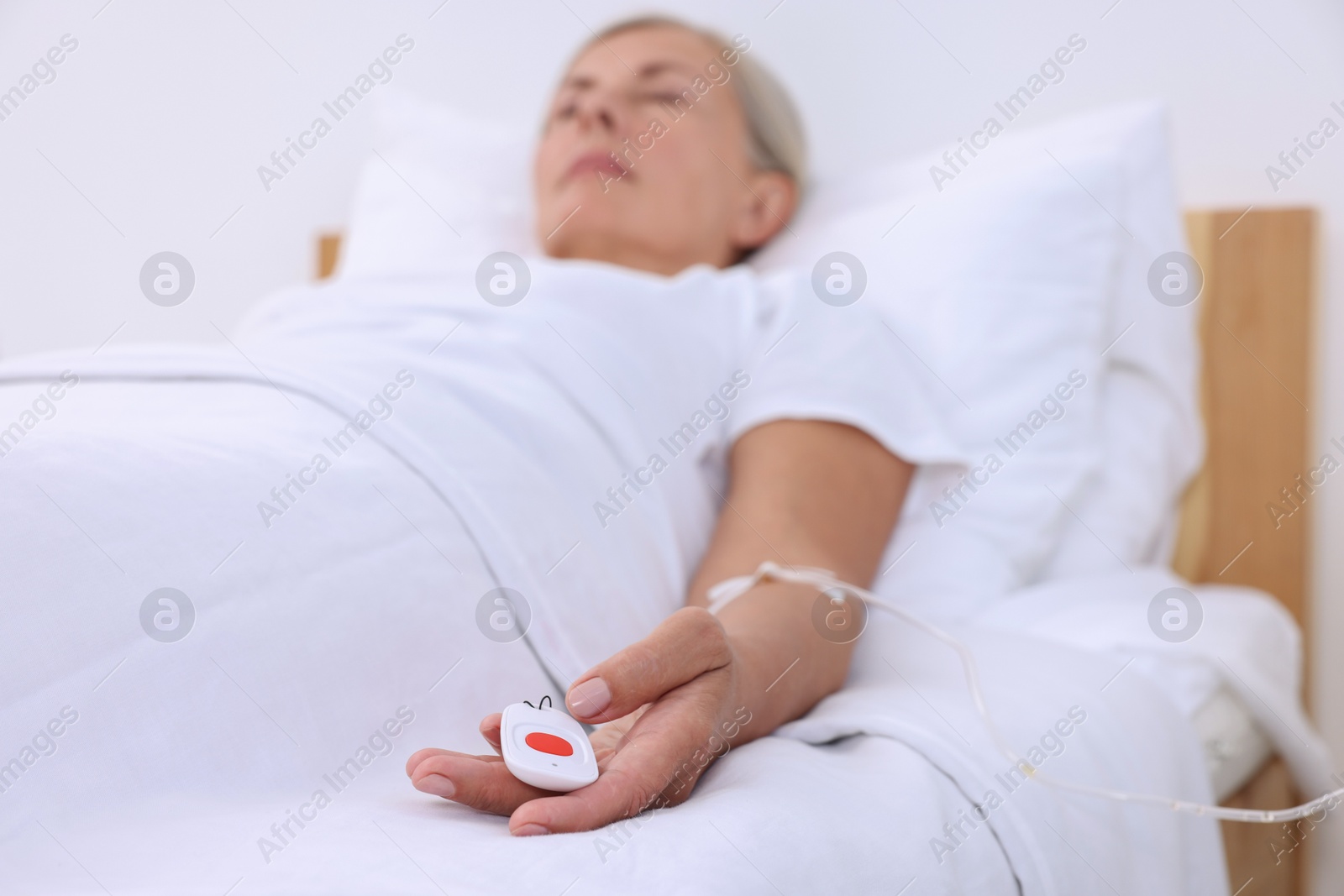 Photo of Senior woman with emergency call button on bed in hospital, selective focus