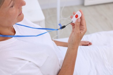 Senior woman with emergency call button on bed in hospital