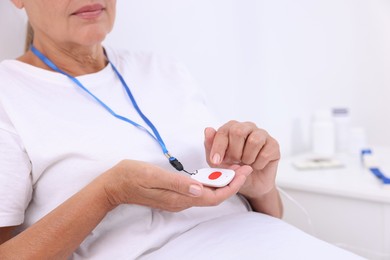 Senior woman with emergency call button on bed in hospital, closeup