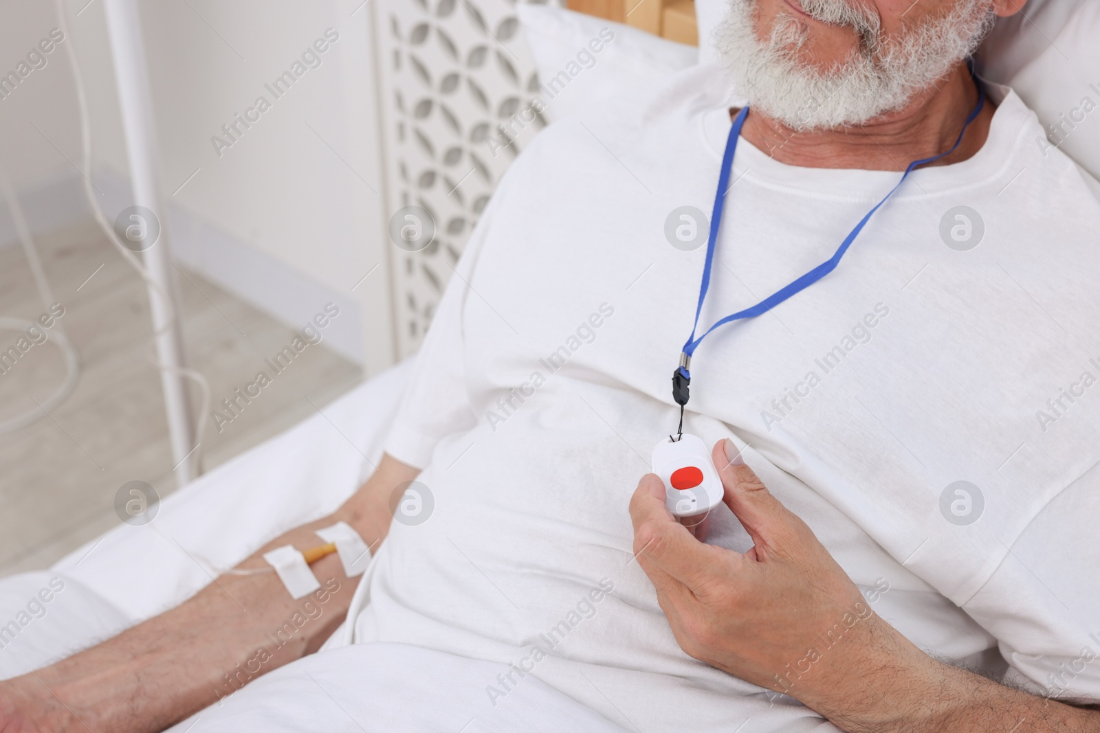 Photo of Senior man with emergency call button on bed in hospital, closeup