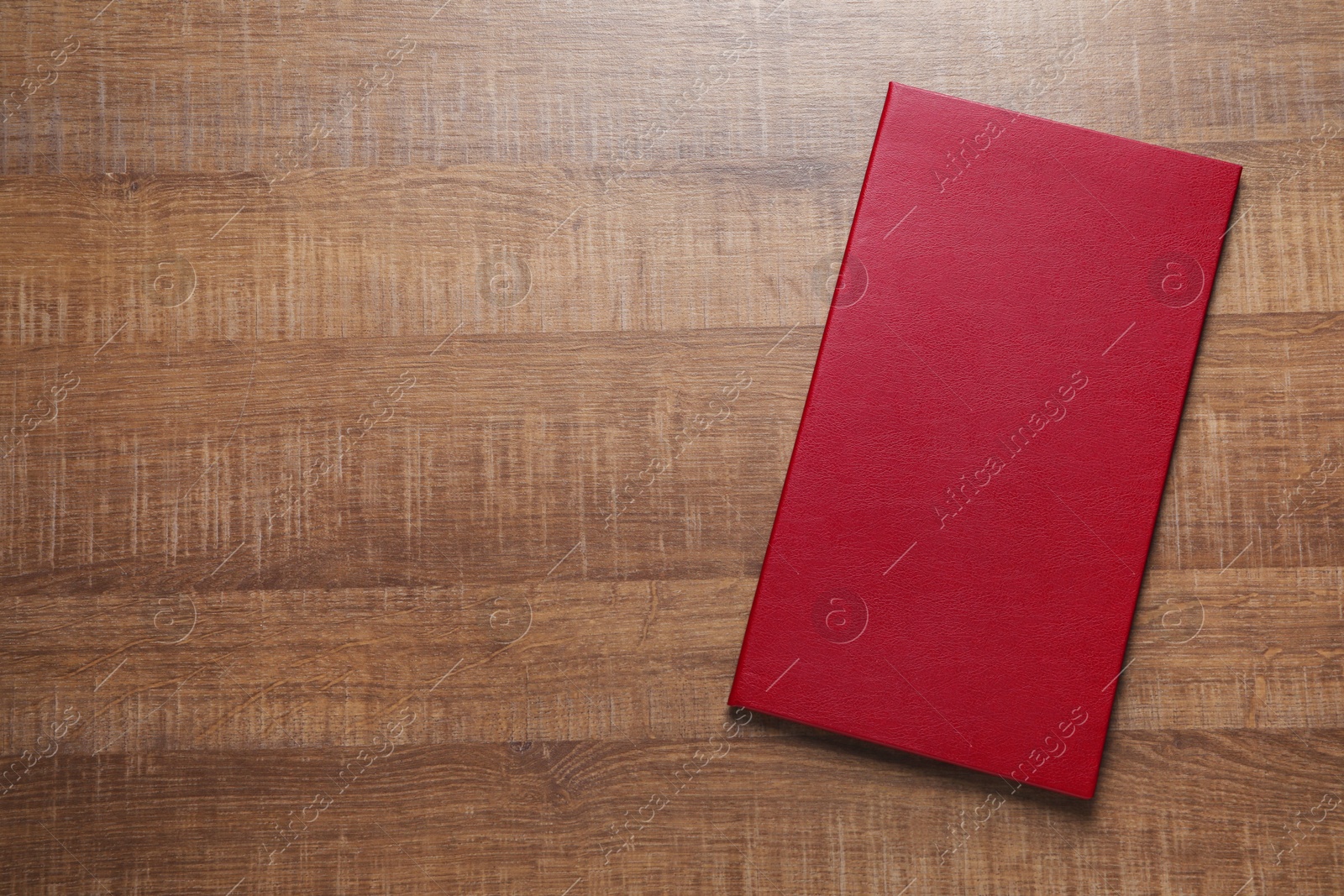 Photo of Hardcover book on wooden table, top view. Space for text