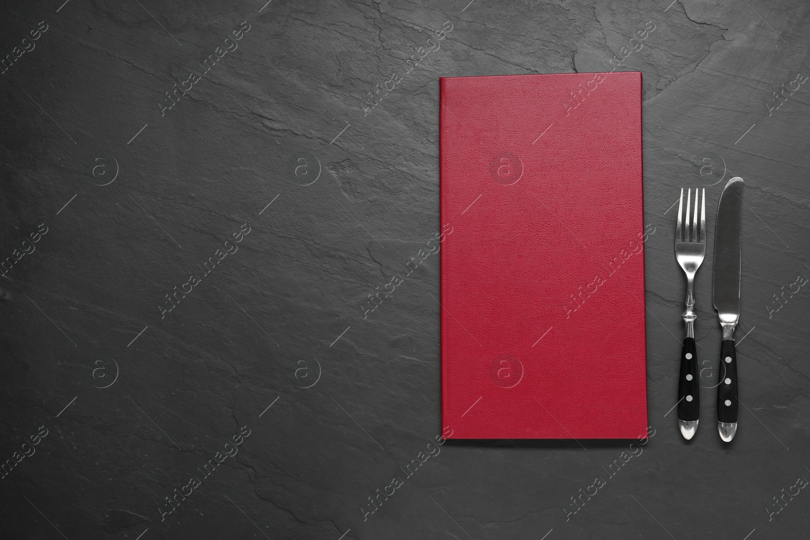 Photo of Hardcover menu and cutlery on grey textured table, flat lay. Space for text