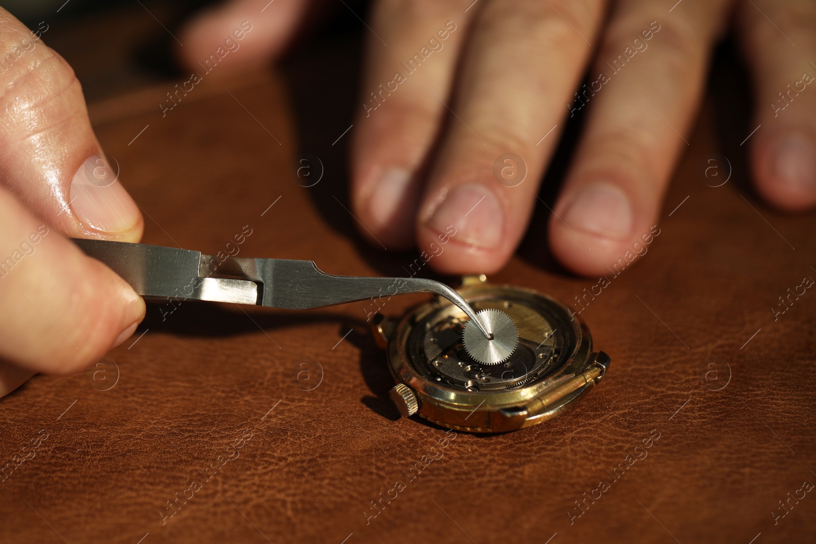 Photo of Man fixing mechanism of vintage wrist watch at table, closeup