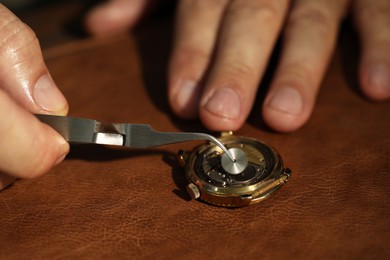 Photo of Man fixing mechanism of vintage wrist watch at table, closeup