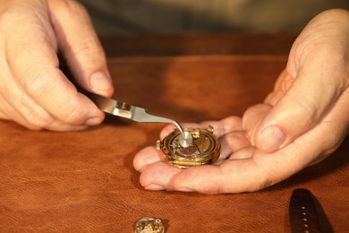 Man fixing mechanism of vintage wrist watch at table, closeup