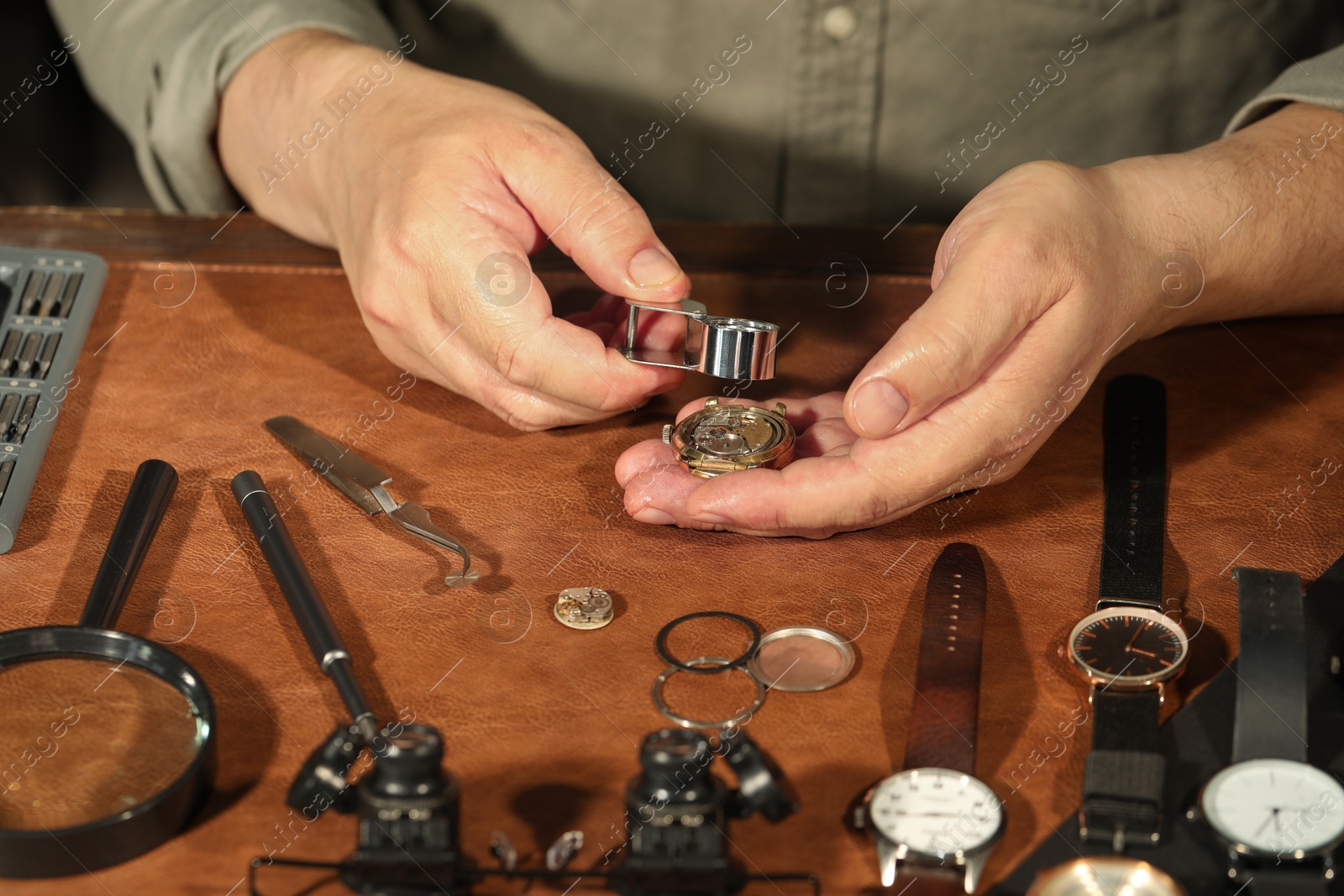 Photo of Man fixing mechanism of vintage wrist watch at table, closeup